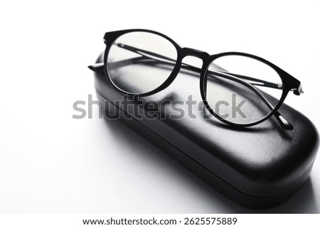 Case with stylish glasses on light background, closeup