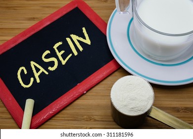 Casein written on chalkboard with a cup of milk and a scoop of milk powder on wood background
