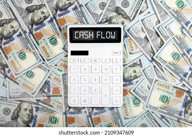 Cash flow concept. Cashflow word on calculator and dollars heap.