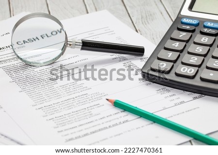cash flow statement with calculator, pen and hand glass