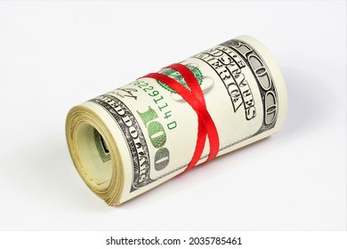 Cash hundred-dollar bills in a roll, tied with a red ribbon. Money to pay for purchases in the store of goods and services.