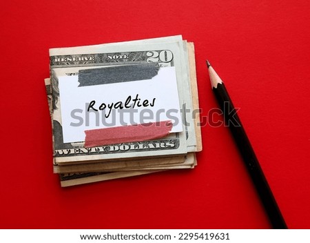 Cash money dollar and pencil on red background with note written ROYALTIES, legally payment made on using their intellectual assets, including book copyrights
