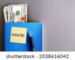 Cash money dollars, pen, blue book on grey background, with sticky note ROYALTIES, concept of passive income from patent or copyright, side income or side hustle from intellectual property royalties