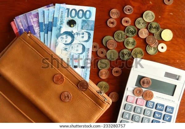 Cash money in a leather wallet, coins and a\
calculator Photo of a bunch of cash money in a leather wallet,\
coins and a calculator