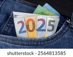 cash in the trouser pocket shows the year 2025, euro banknotes in blue jeans symbolize wealth or tax changes in the new year in europe