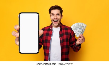 Cashback, Easy Online Money Transfer Concept. Excited young guy holding big smartphone with white blank empty cell screen for mock up and cash money dollar banknotes in hand, isolated on studio wall - Shutterstock ID 2135794249