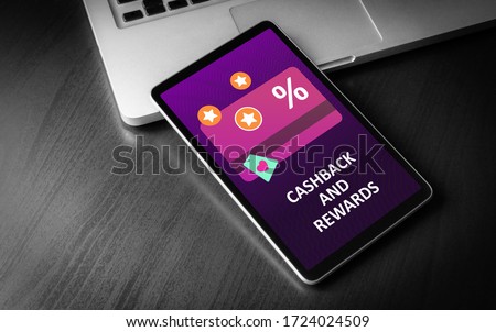 Cashback and Rewards - loyalty program and retail customer money refund service concept. Tablet PC lying on a wooden table with cashback discount card and rewarding marketing points on the screen