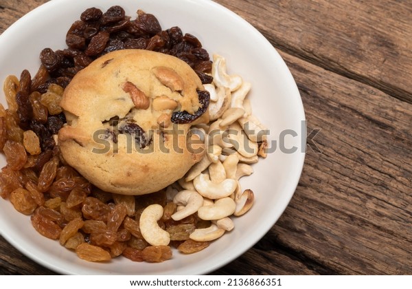 Cashew nuts raisin cookies in\
plate on wood background close up, top view, food and drink\
concept.