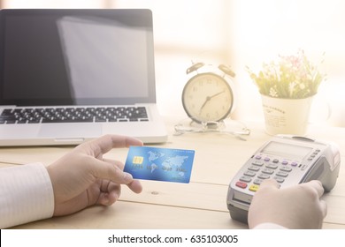 Cashier hand holding a Credit card over EDC machine or credit card terminal. This is fake credit card.
