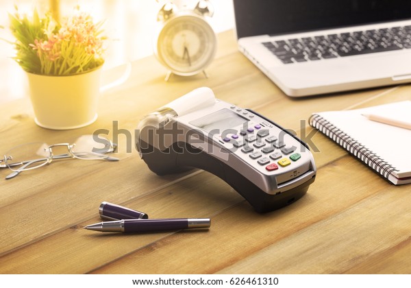 Cashier hand holding a\
Credit card over EDC machine or credit card terminal with\
calculator and glasses.