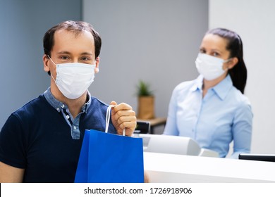 Cashier In Retail Shop Or Store At Counter Wearing Face Mask