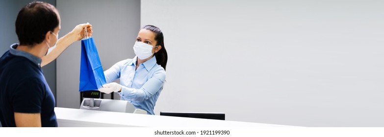 Cashier In Retail Shop Or Store At Counter Wearing Face Mask