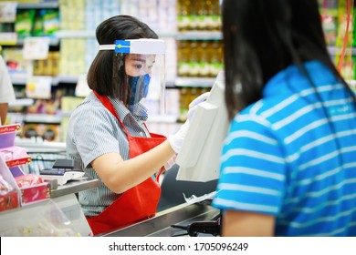 Kasse- oder Supermarktmitarbeiter in medizinischer Schutzmaske und Gesichtsschild, die im Supermarkt arbeiten. Ausbruch der Covid-19-Ausbreitung  