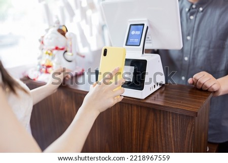 cashier using digital device for payment. Man waiter calculates young woman in cafe by mobile phone via QR code of Alipay or Wechat pay (popular payment metod in China). The concept of the restaurant