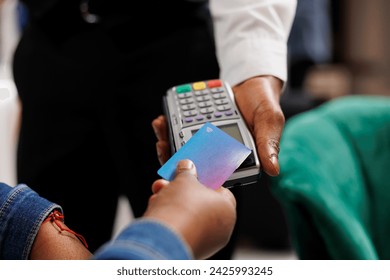 Cashless payments in hotels. Hospitality worker holding pos terminal accepting credit card payment from customer, close up of person making convenient and quick contactless transaction - Powered by Shutterstock