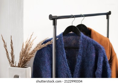 Cashmere Jumper And Coat On Hangers In A Wardrobe In A White Interior. Classic Women's Fashion Clothes.