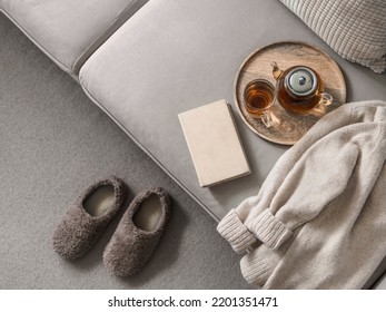 Cashmere sweater, reading and serving tray on gray sofa. Warm weekend at home aesthetics. Detail of cozy scandinavian winter interior. Warm soft winter slipper on carpet at home - Shutterstock ID 2201351471