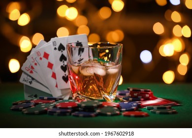 Casino chips, cards and alcohol drink on green table against blurred lights. Straight poker combination - Powered by Shutterstock