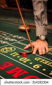 Casino Dealer Pushing A Pair Of Dice On A Craps Table