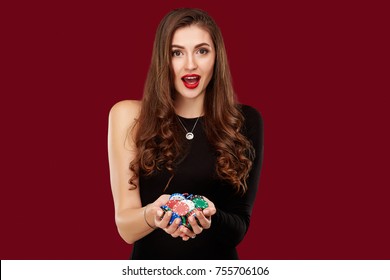 Casino, Gambling, Poker, People And Entertainment Concept - Woman Poker Player In Black Dress With Chips In Hands On Red Background.