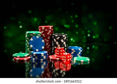 Casino. Game chips and dice lie on the table against a blurred dramatic background. Game chips for betting in gambling. Dice. Poker chips. - Powered by Shutterstock