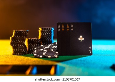 Casino, Online Casino. Black Poker Cards And Stacks Of Black Chips On A Green Gambling Table. Multicolored Background. There Are No People In The Photo. Night Club, Casino, Gambling Business.