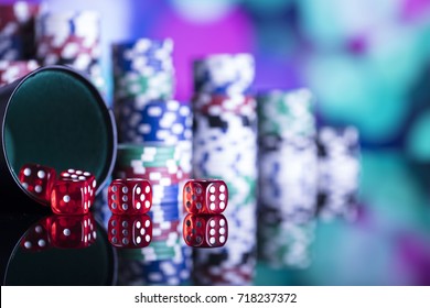 Casino theme. High contrast image of casino roulette, poker game, dice game, poker chips on a gaming table, all on colorful bokeh background. 