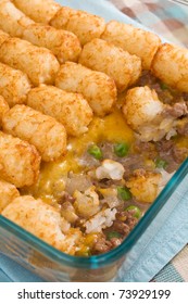 Casserole Made Of Tater Tots, Cheddar Cheese, Ground Beef, Peas, And Onions.