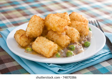 Casserole Made Of Tater Tots, Cheddar Cheese, Ground Beef, Peas, And Onions.