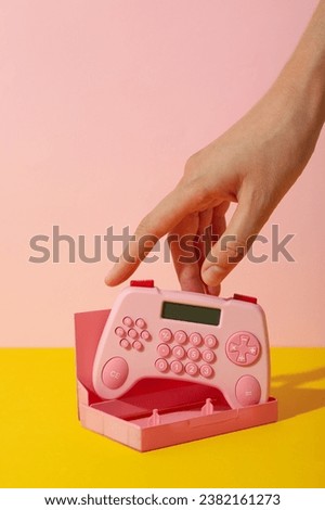 Cassette case and calculator in hand on pink background