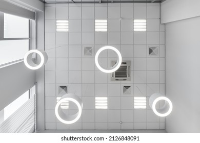 cassette suspended ceiling with square and round halogen spots lamps and drywall construction in empty room in apartment or house. Stretch ceiling white and complex shape. Looking up view