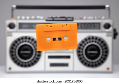 A cassette tape in mid air with ghettoblaster in background