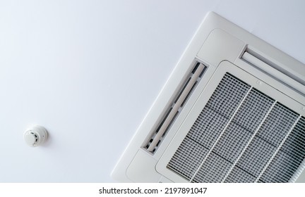 Cassette Type Air Conditioner And Smoke Detector Mounted On Ceiling Wall. Air Duct On Ceiling In Hotel. Air Heading Unit On Gypsum Wall. Cool System In The Building. Air Flow And Ventilation System. 