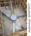 Cast iron drainage inspection chamber and pipes on a construction site with visible rebar and concrete base. Industrial construction photo for design and documentation.