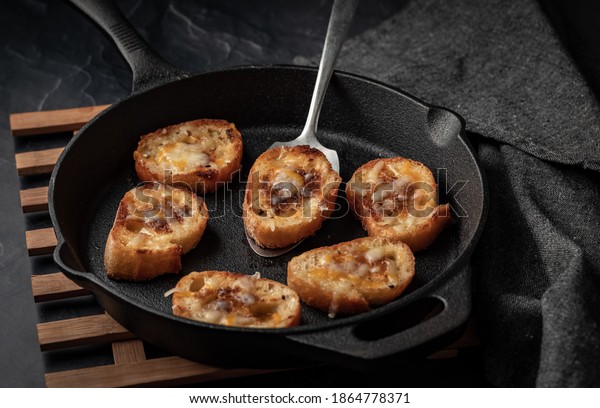 Cast iron fry pan filled with fried cheese bread\
rounds ready for serving.