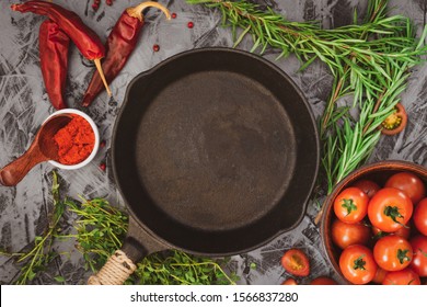 Cast iron pan on concrete background with red ripe tomatoes and red pepper