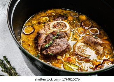 Cast iron pan with ossobuco made of cross cut veal shank. ossobuco meat stew. Gray background. Top view