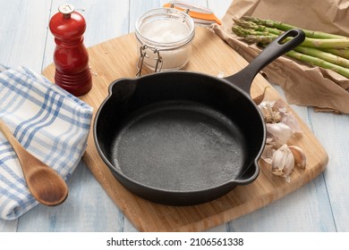 Cast iron skillet on a wooden board with kitchen items.