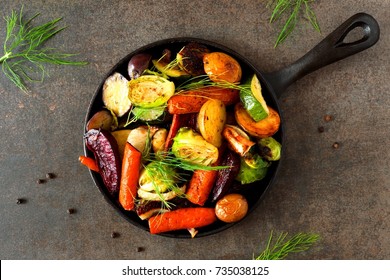 Cast Iron Skillet Of Roasted Autumn Vegetables, Above View Over A Dark Stone Background