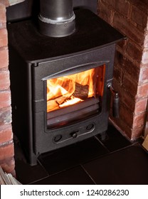 Cast iron wood burner in old brick fireplace burning chopped wood