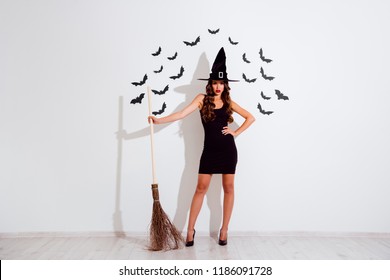 I'll Cast A Spell On You. Full Length, Legs, Body, Size Portrait Of Beautiful, Attractive, Pretty, Dreamy, Charming Curly Brunette Lady With Broom At Hands  Isolated On White Background