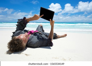 Castaway businessman relaxing with wifi on a tropical beach using his tablet computer - Shutterstock ID 1565534149