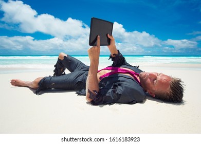 Castaway businessman relaxing with wifi on a tropical beach using his tablet computer - Shutterstock ID 1616183923