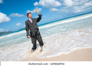 Castaway Businessman Standing On A Tropical Beach Trying To Read A Message In A Green Bottle