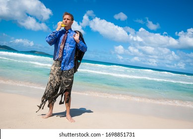 Castaway businessman standing in tattered suit using a banana as a mobile phone to have an imaginary conversation on a tropical beach - Shutterstock ID 1698851731