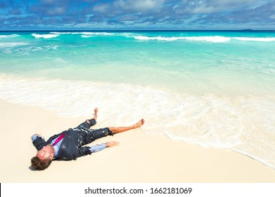 Castaway office worker washed up on a tropical beach in a ragged torn suit - Shutterstock ID 1662181069