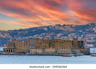 The Castel dell'Ovo (Egg Castle) the oldest standing medieval fortification in Naples on the Gulf of Naples, Italy. Historic city in the background, on the hill. Sunset light. - Shutterstock ID 1949362363