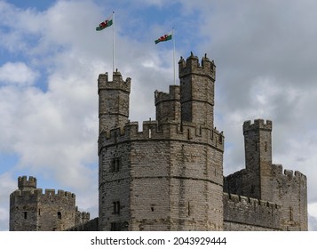 Castellated Tops Of The Eagle Tower, Well Tower And Queen's Tower Of Caernarfon Castle With Two Welsh Dragon Flags Flying In The Wind Above The Eagle Tower.