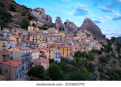 Castelmezzano Italy reveals its charm as colorful houses cling to steep cliffs, surrounded by dramatic rock faces under a vast sky. The quaint village invites exploration and admiration  - Powered by Shutterstock