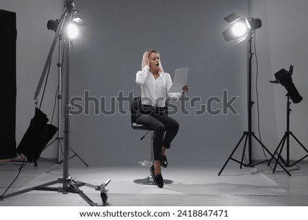 Casting call. Emotional woman with script performing against grey background in studio
